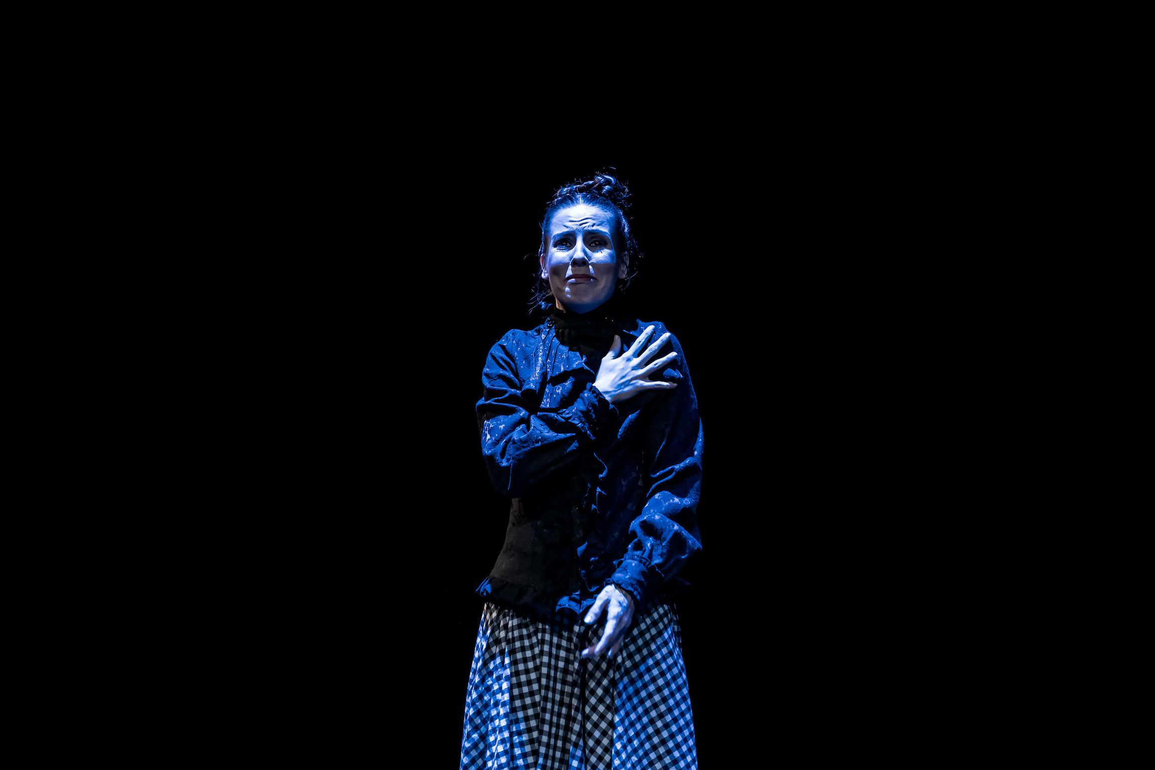 Eliška standing on stage crying with one hand on her chest.