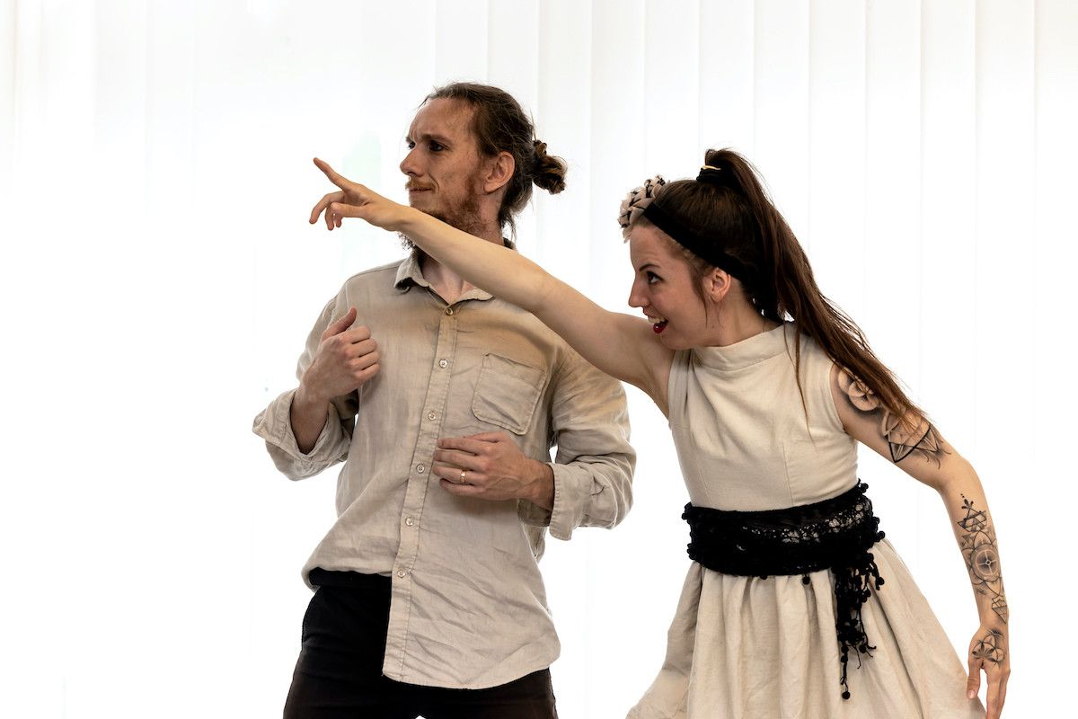 Tomaš, looking a bit confused, looking into the direction pointed by Eliška, who looks excited