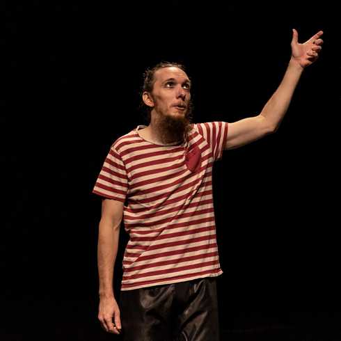 Tomaš on stage in little boy’s clothes, holding his invisible mother’s hand